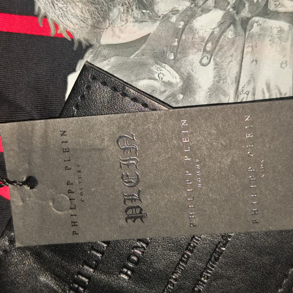 Black tag with 'PHILIPPE PLEIN' branding on a textured background